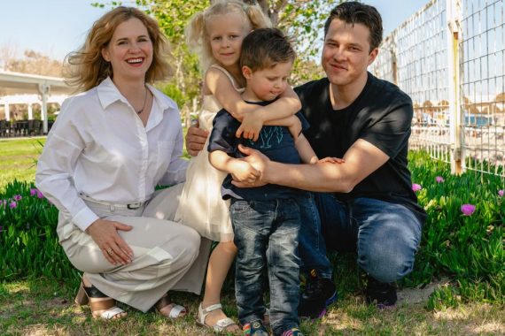 Family of four enjoying a sunny day outdoors in Kemer, smiling and spending quality time together.